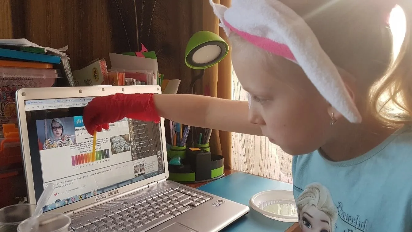 Ученица капает реактив в планшетку, на экране ноутбука — шкала индикаторов